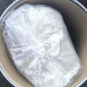 White plastic bag sealed inside a brown metal trash can; contents not visible, suggesting trash storage or waste inside the can