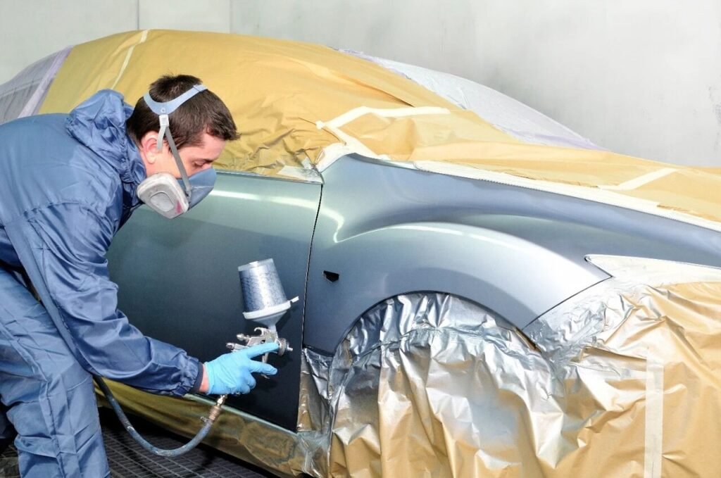Workers spray painting a car