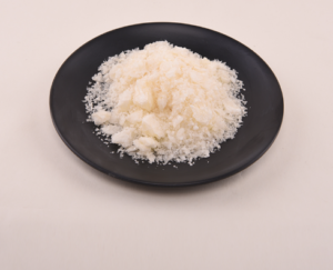 Pile of grated white cheese on a black plate, centered against a light background.