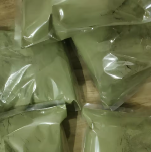Green rectangular blocks wrapped in clear plastic on a wooden surface.