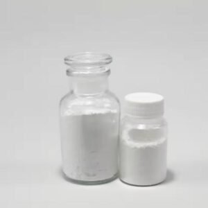 Two glass bottles containing white powder on a pale surface, one open with a glass stopper and the other closed with a white cap.