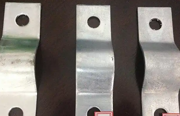 Three galvanized metal brackets with circular screw holes, arranged side by side on a dark background.