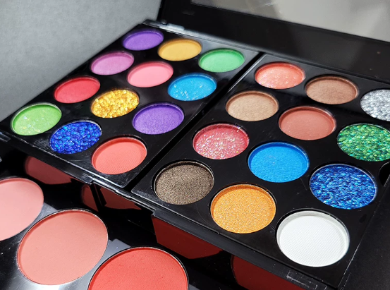 Makeup – quartz-chem Two open makeup palettes with many bright, round eyeshadows in assorted colors and blush/face powders nearby
