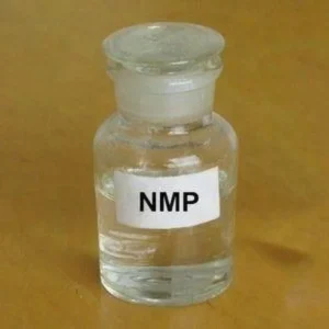 N-Methylpyrrolidone Glass vial with a white label reading 'NMP' on a wooden surface, containing a clear liquid.